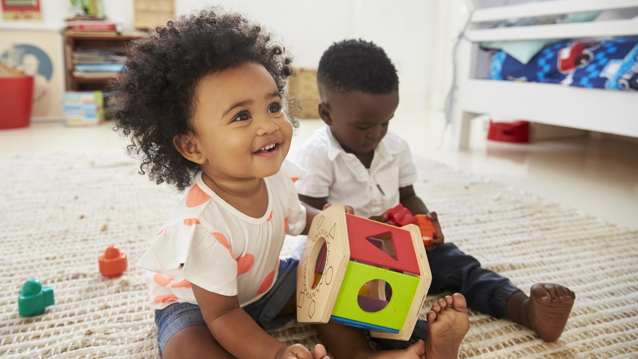 Deux jeunes enfants assis sur un tapis.