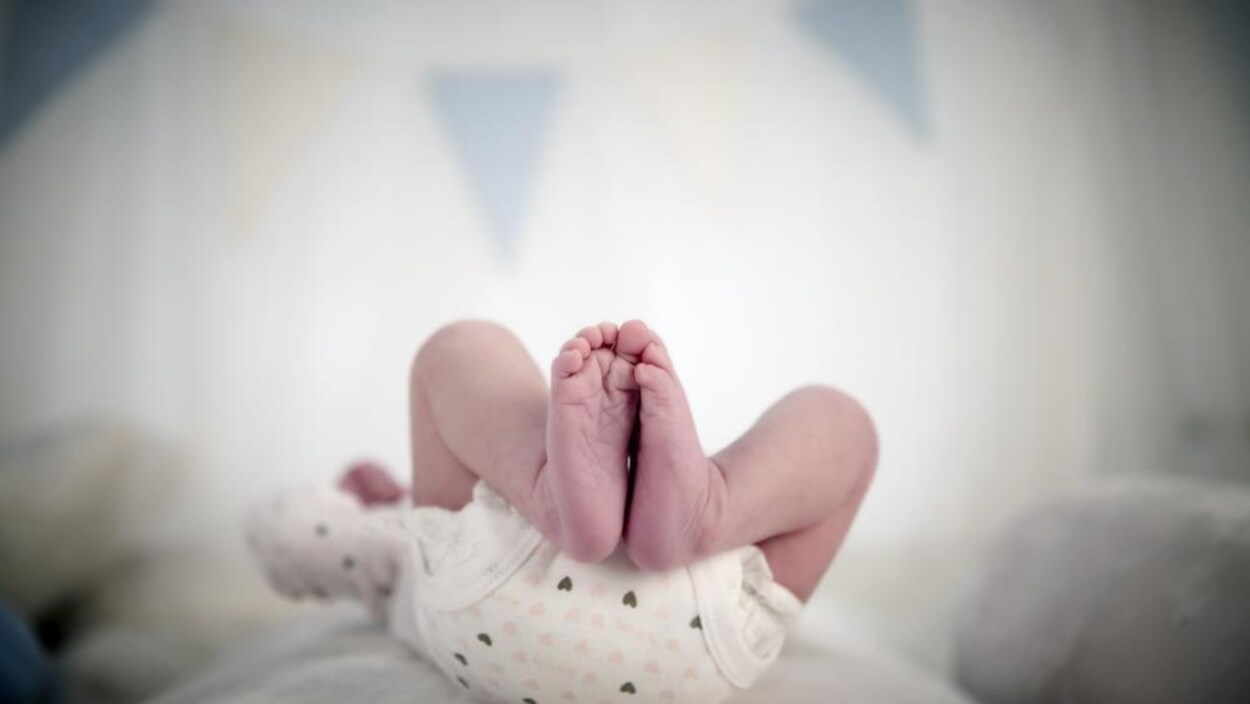 On voit les jambes d'un bébé couché sur le dos.