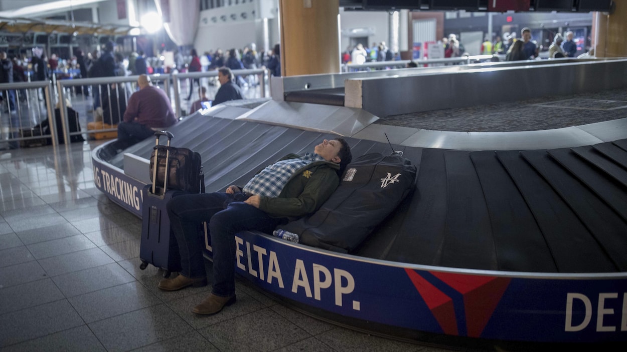 Un voyageur dort sur un carrousel à bagages à l'aéroport international Hartfield-Jackson d'Atlanta. Un voyageur dort sur un carrousel à bagages à l'aéroport international Hartfield-Jackson d'Atlanta.