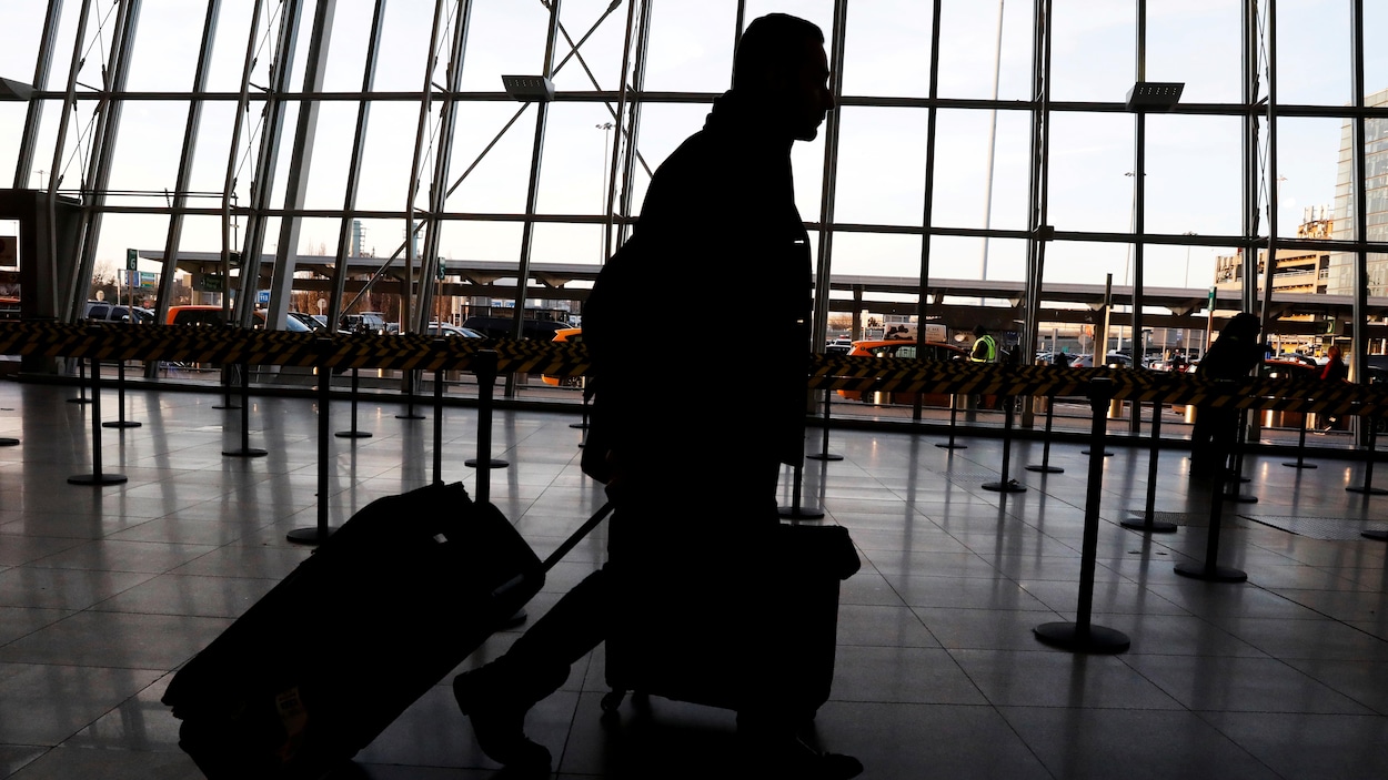 Un voyageur traînant sa valise dans un aéroport.