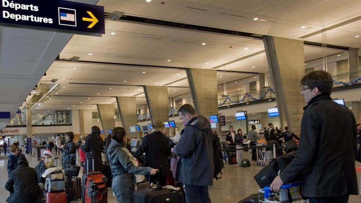 Des passagers font la file pour enregistrer leurs bagages à l'aéroport international Pierre-Elliott-Trudeau de Montréal. Des passagers font la file pour enregistrer leurs bagages à l'aéroport international Pierre-Elliott-Trudeau de Montréal.