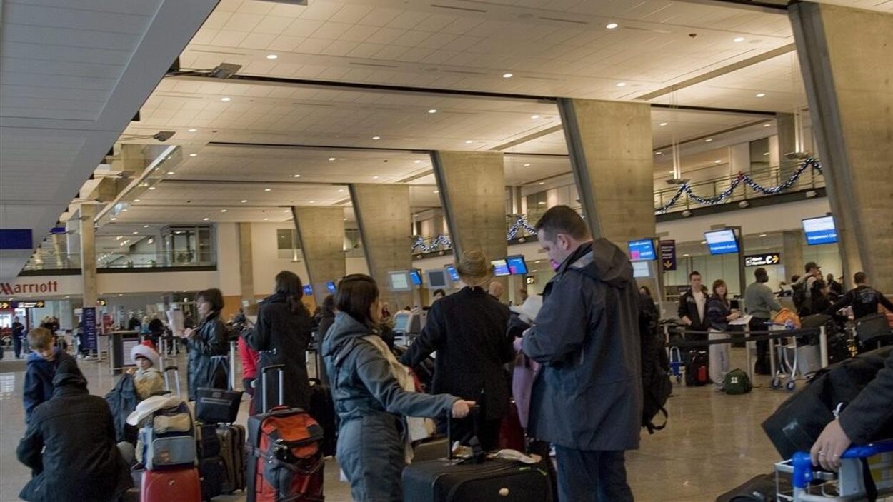 Des passagers font la file pour enregistrer leurs bagages à l'aéroport international Pierre-Elliott-Trudeau de Montréal.