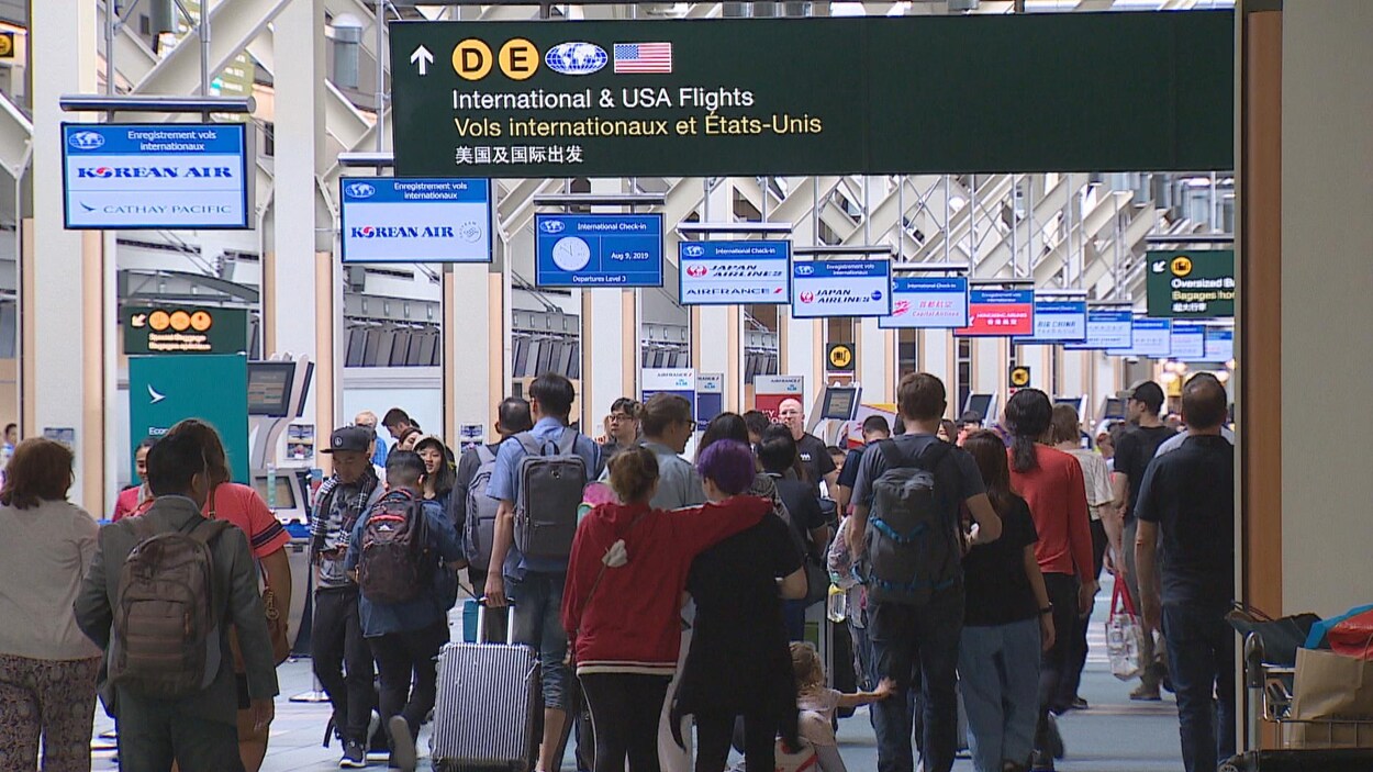 Des voyageurs marchent dans un aéroport.