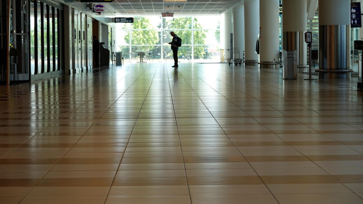 Un homme seul dans un grand couloir de l'aéroport de Winnipeg.