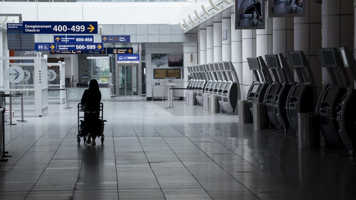 Une femme marche seule dans un corridor d'un aéroport.