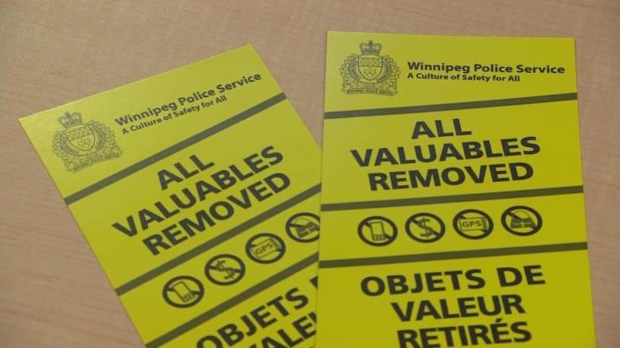 Une afichette jaune et bilingue du service de police de la ville de Winnipeg indique: Objets de valeur retirés.