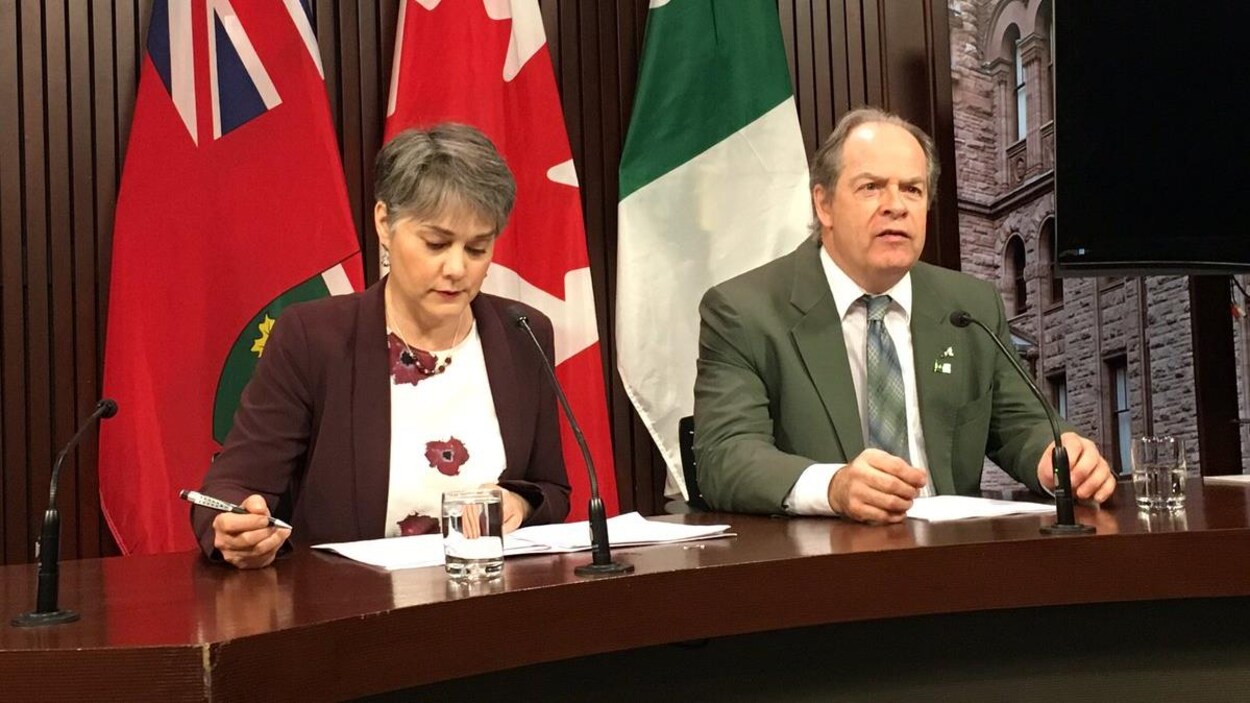 Une femme et un homme en point de presse.