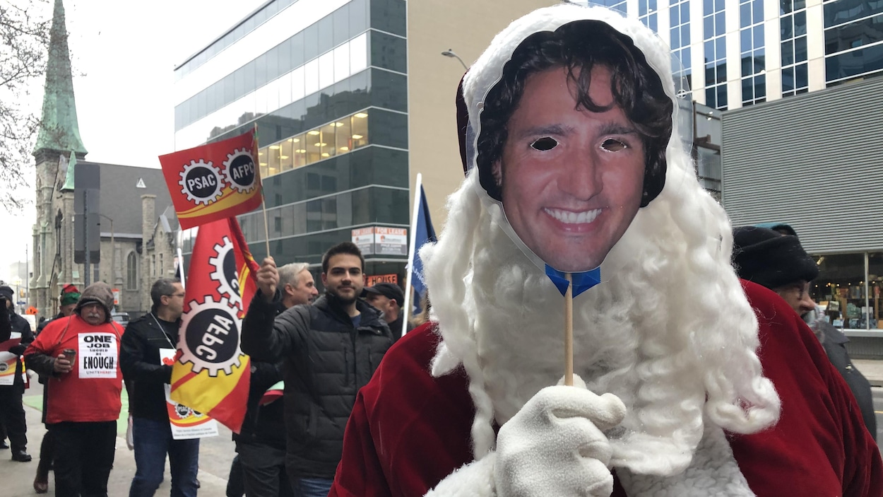 Un manifestant avec un masque de Justin Trudeau devant les yeux.