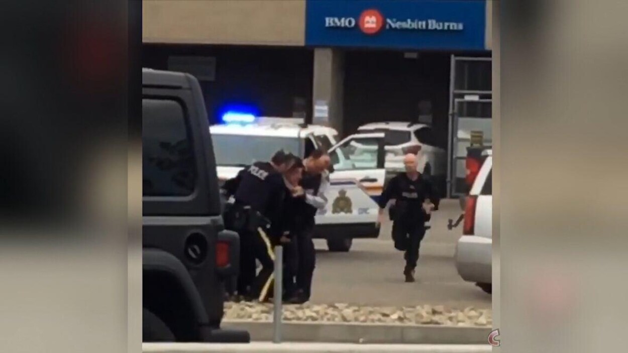 Un policier court vers deux autres agents qui tentent de maîtriser un suspect.