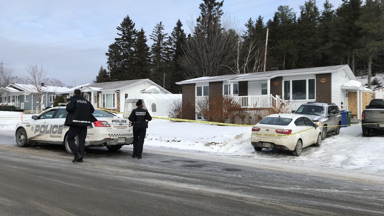 Des policiers se trouvent à l'extérieur d'un périmètre de sécurité érigé près d'une résidence.