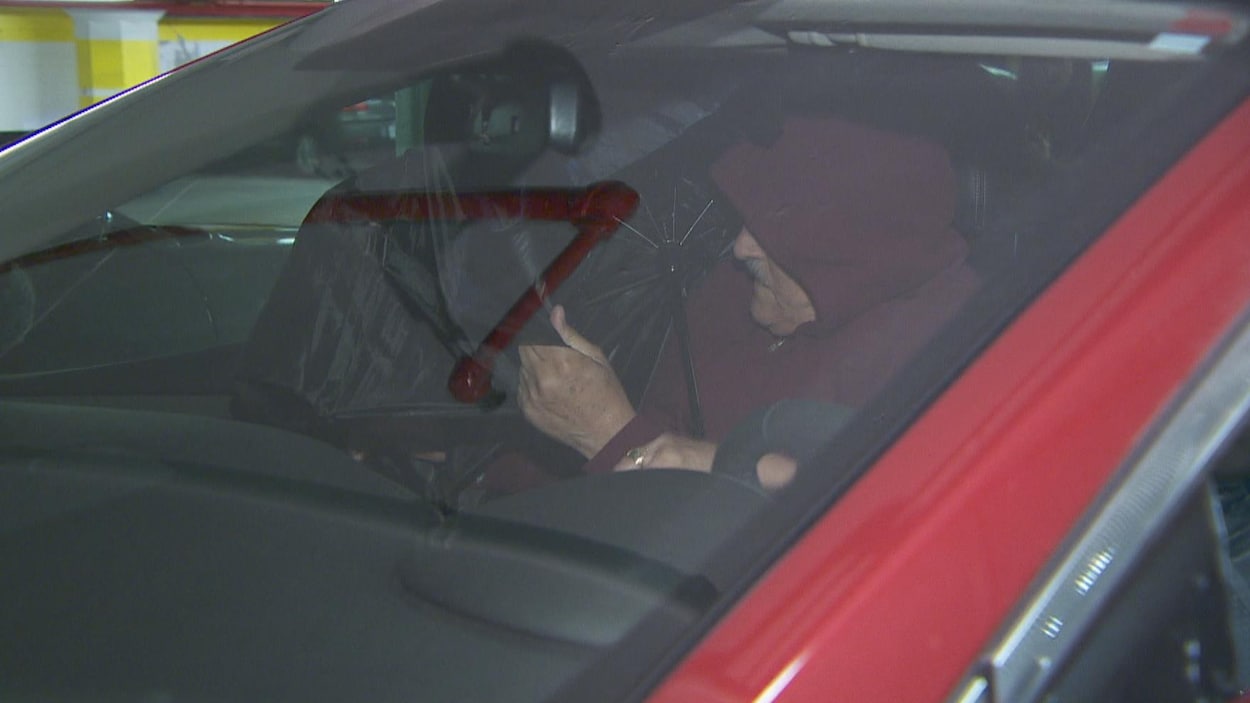 On voit Claude Trachy qui entre dans sa voiture pour échapper à la vigilance des médias en sortant du tribunal.