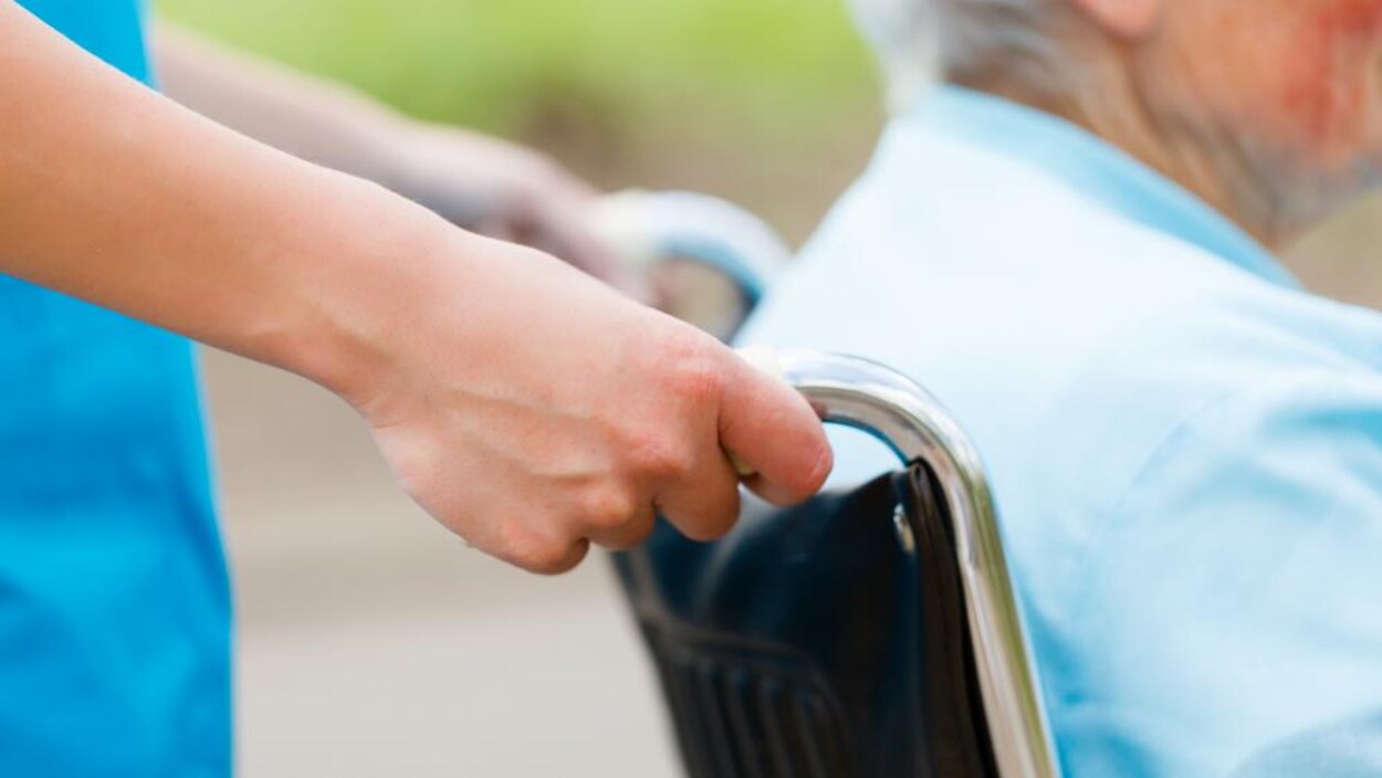 Une infirmière pousse une chaise roulante. Une infirmière pousse une chaise roulante.