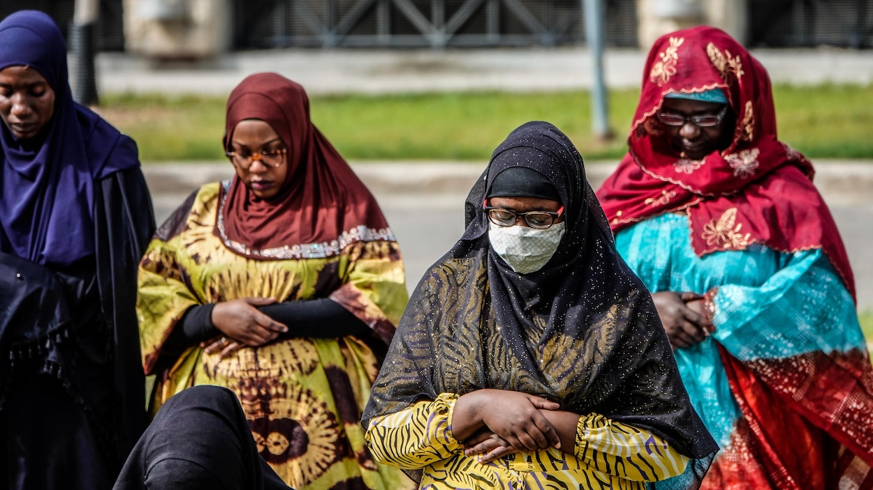 Des femmes voilées en train de prier avec l'une d'elles portant un masque.