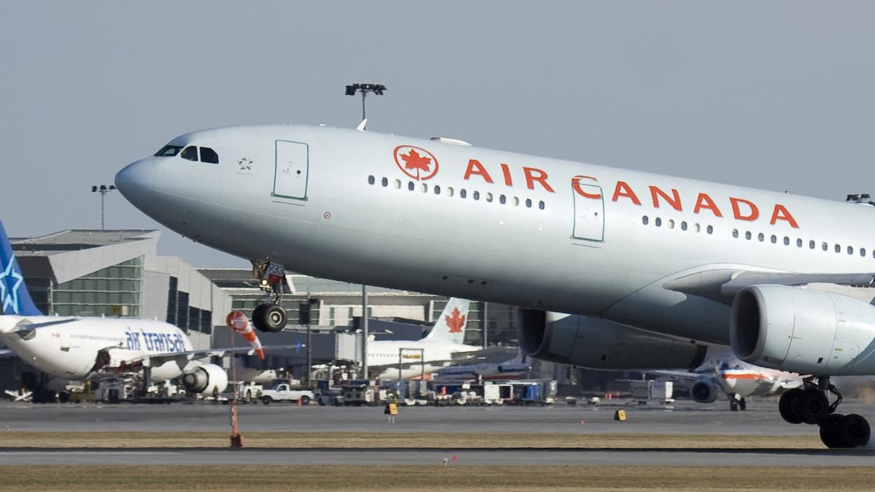 Un avion d'Air Canada passe devant un autre d'Air Transat à l'aéroport Montréal-Trudeau.