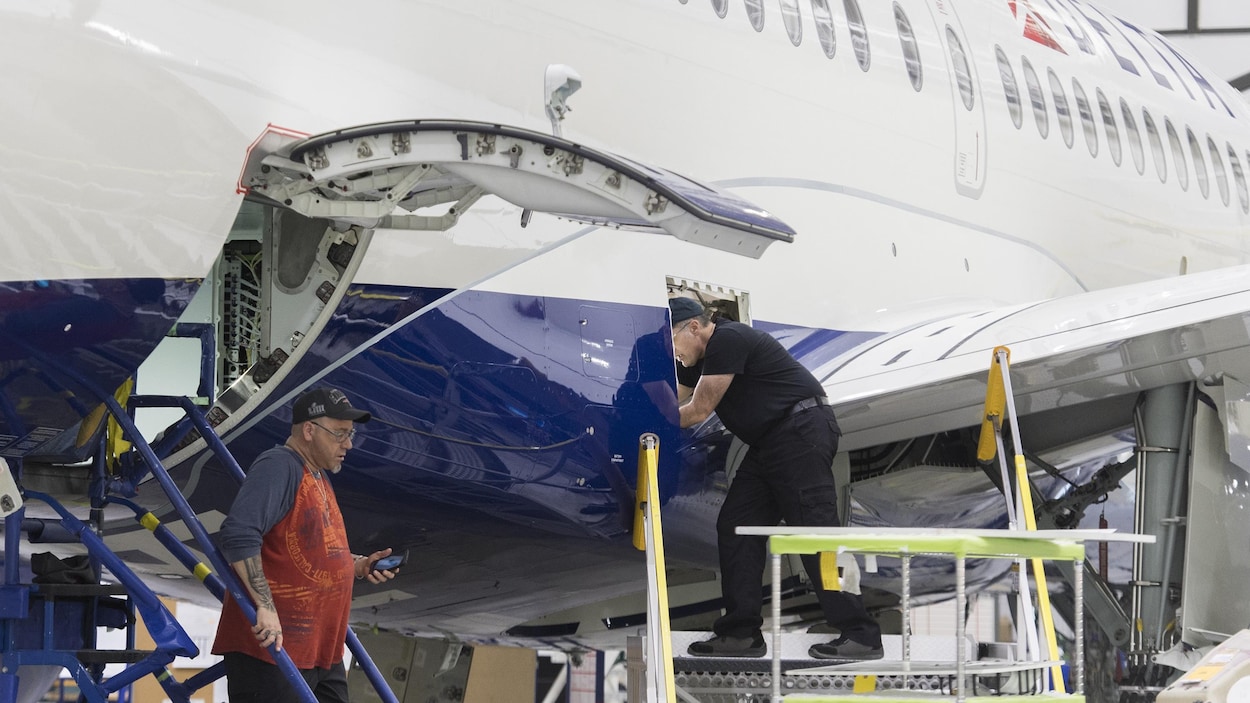 Des employés travaillent sur un avion