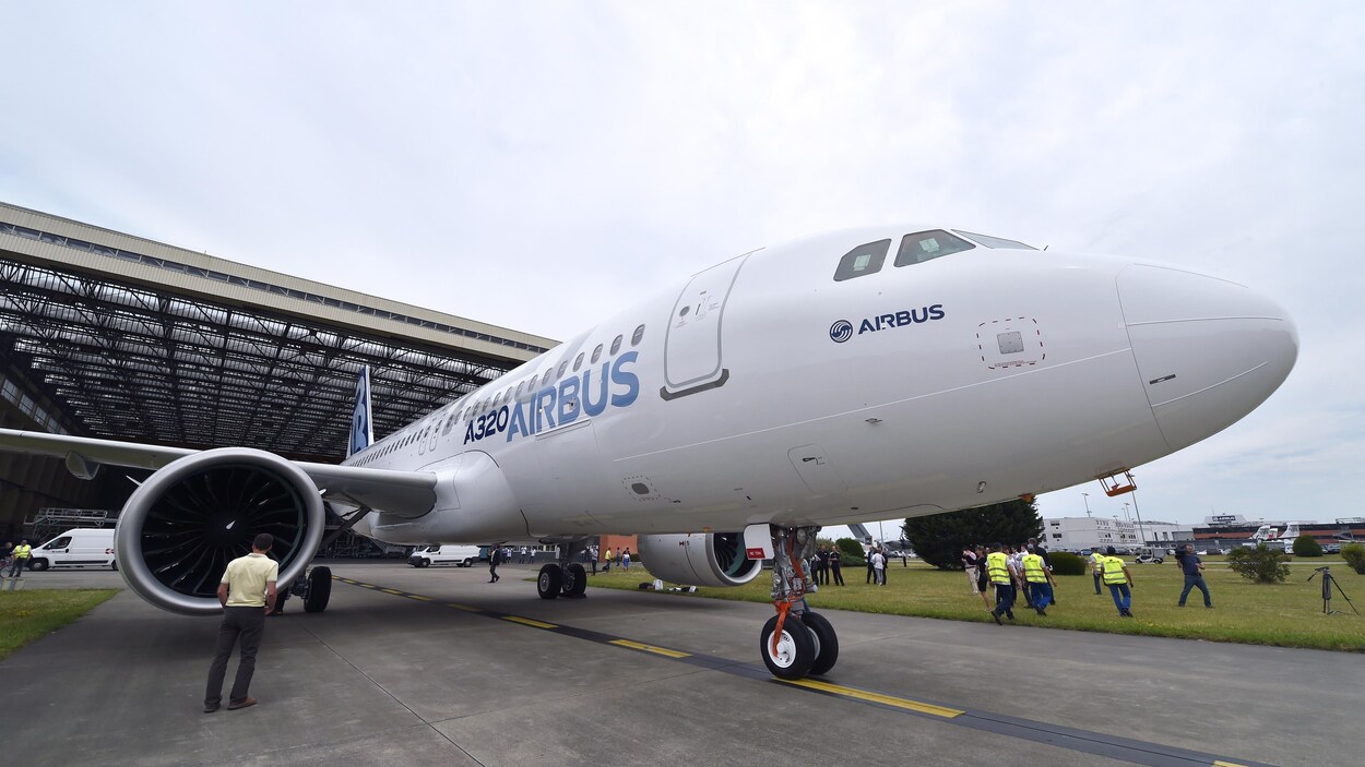 Un avion tout neuf sort d'un hangar sur une piste.