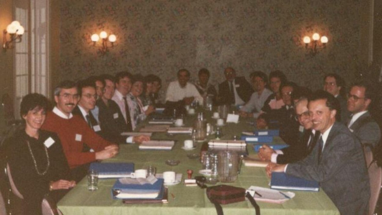 Des personnes attablées lors d'une réunion, dans les années 90.