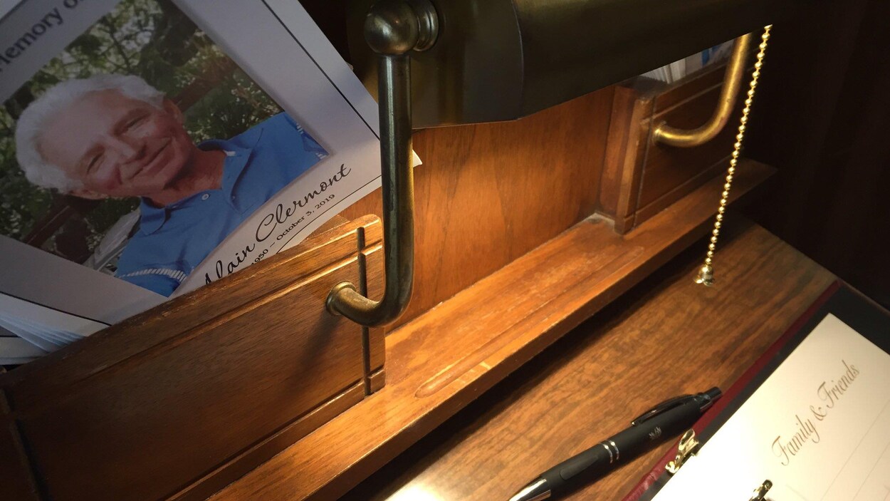 Une écritoire avec un livre de condoléances et un carnet. La photo d'Alain Clermont imprimée en première page.