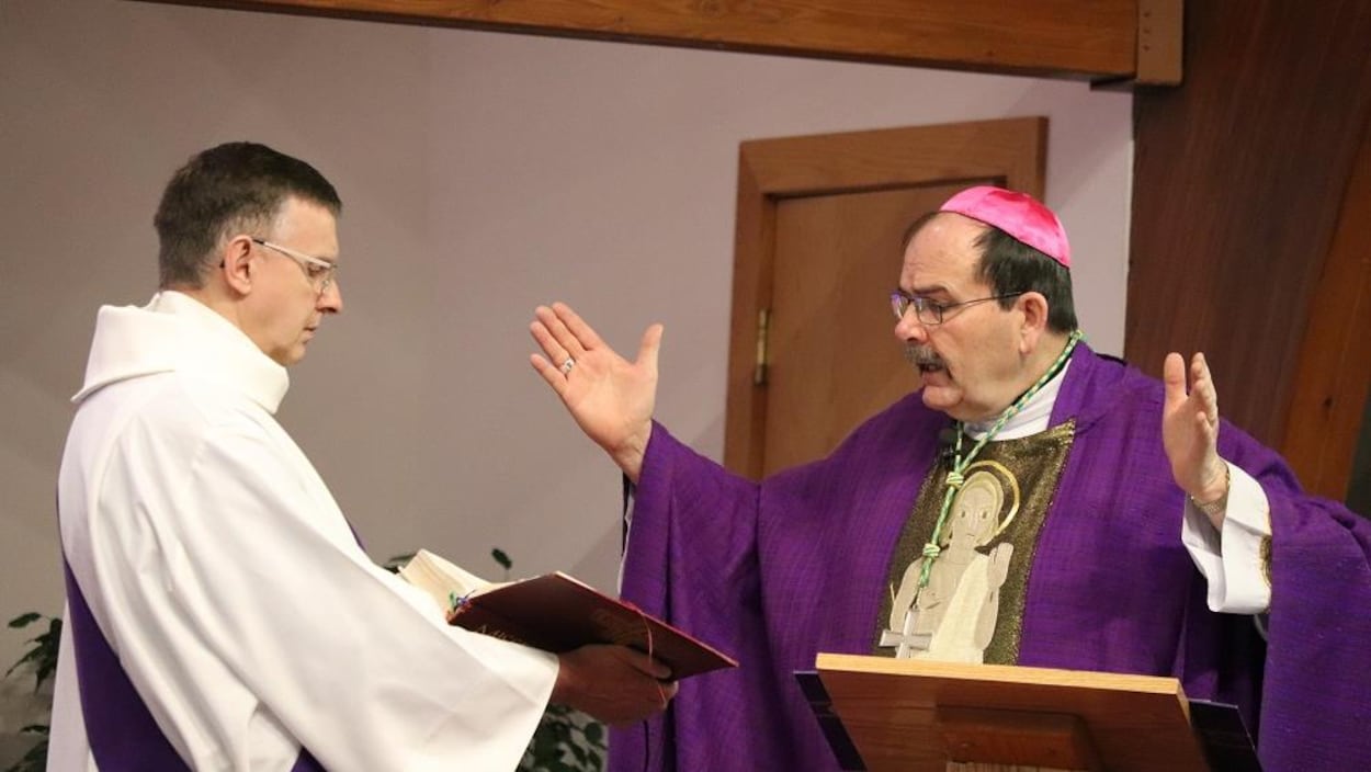 Monseigneur LeGatt lit un passage d'un livre tenu par un assistant.