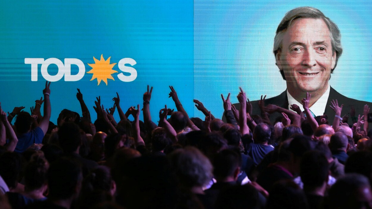Des partisans lèvent les bras devant l'affiche sur fond bleu de leur candidat Alberto Fernandez.