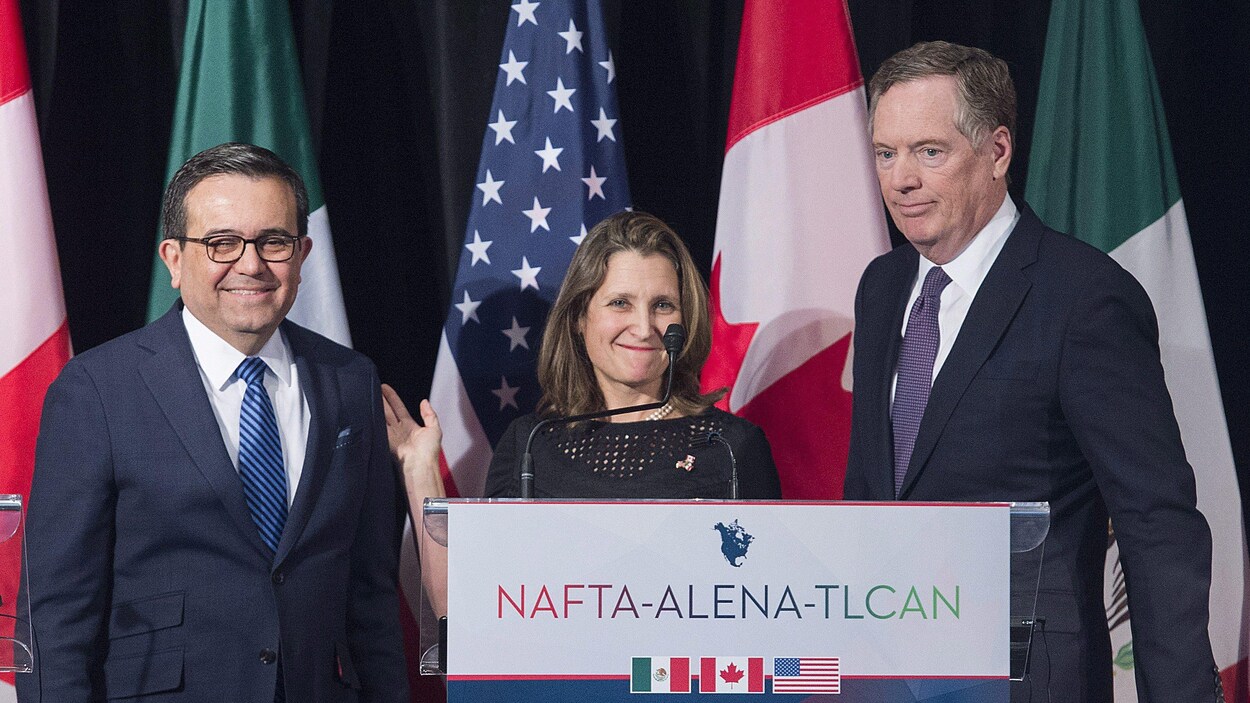 Ildefonso Guajardo Villarreal, Chrystia Freeland et Robert Lighthizer se tiennent devant les drapeaux canadien, mexicain et américain lors d'une conférence de presse.
