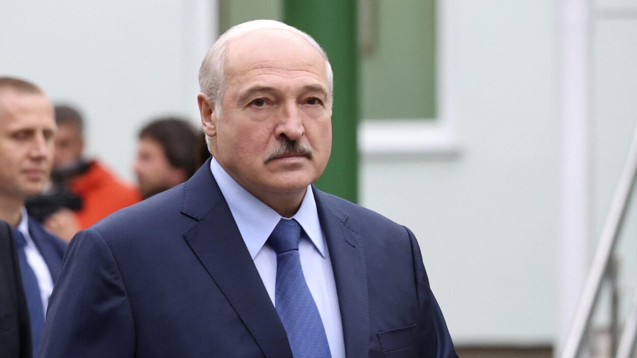 Alexandre Loukachenko marche dehors entouré de gens.