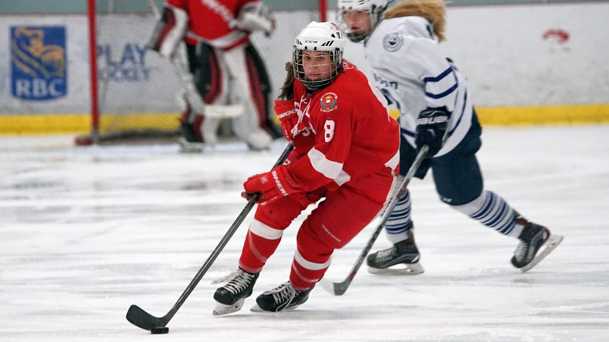 La Magogoise Alexie Guay joue également pour les Spartans de Stanstead. On la voit ici arborer l'habit rouge des Spartans, en pleine action sur la glace.