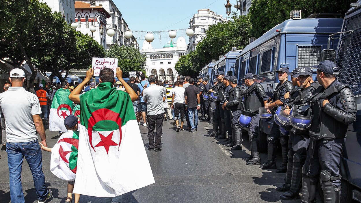 Des manifestants marchent à côté de policiers.