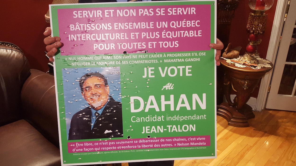 Le candidat Ali Dahan montre une pancarte criblée de projectiles. Le candidat Ali Dahan montre une pancarte criblée de projectiles.
