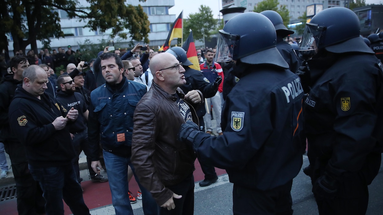 Un manifestant apostrophe un policier casqué en Allemagne.