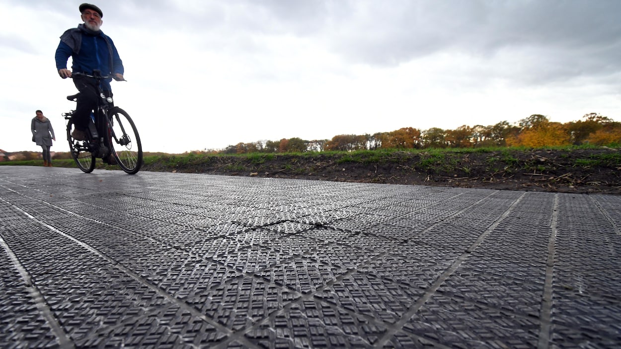 Un cycliste roule sur une piste cyclable faite de cellules photovoltaïques.