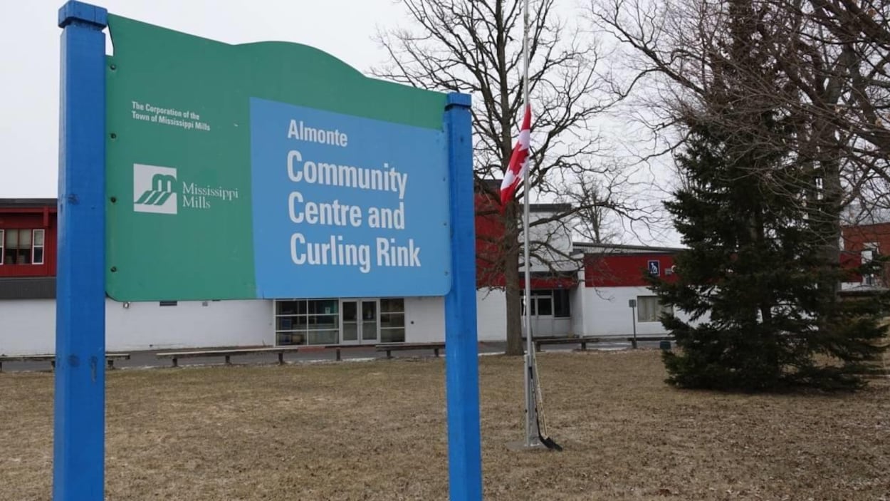 En avant-plan, un panneau sur lequel on peut lire « Almonte Community Centre and Curling Rink ». En arrière-plan, un drapeau canadien en berne avec deux bâtons de hockey. En avant-plan, un panneau sur lequel on peut lire « Almonte Community Centre and Curling Rink ». En arrière-plan, un drapeau canadien en berne avec deux bâtons de hockey.
