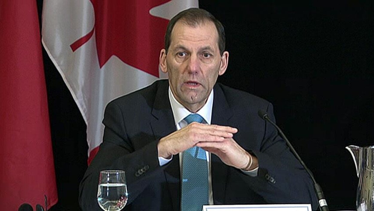 Un homme enu conférence de presse avec un drapeau du Canada à l'arrière-plan Un homme enu conférence de presse avec un drapeau du Canada à l'arrière-plan