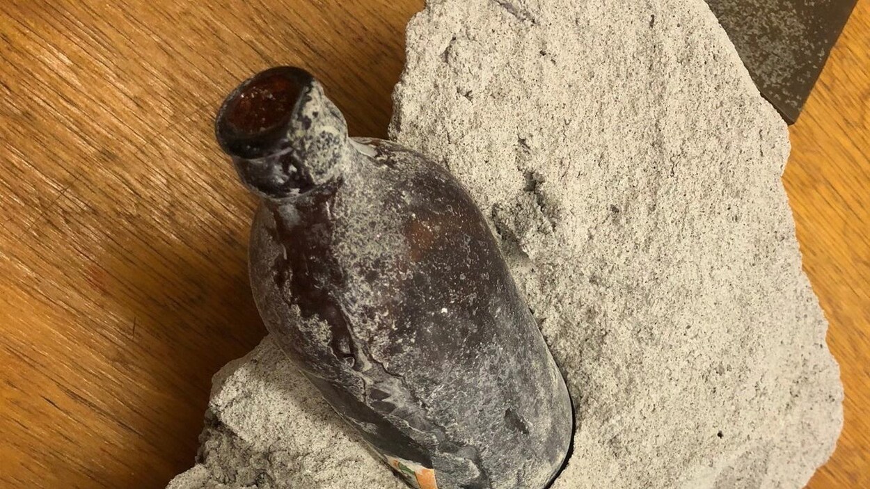 Une bouteille de bière est encastrée dans un bloc de béton. Une bouteille de bière est encastrée dans un bloc de béton.