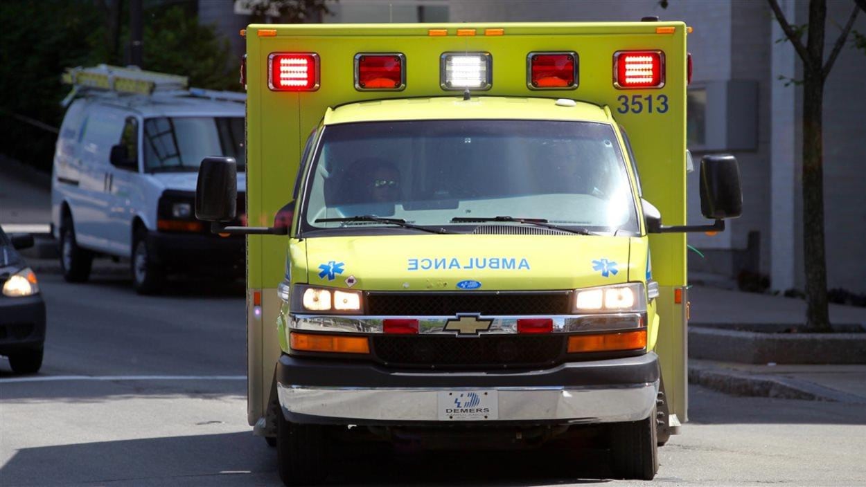 Une ambulance, phares allumés, tourne sur un coin de rue