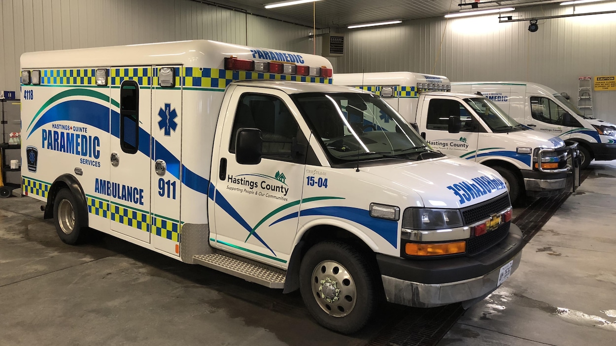 Trois ambulances stationnées dans un grand garage qui sert à l'entretien et la préparation des véhicules.