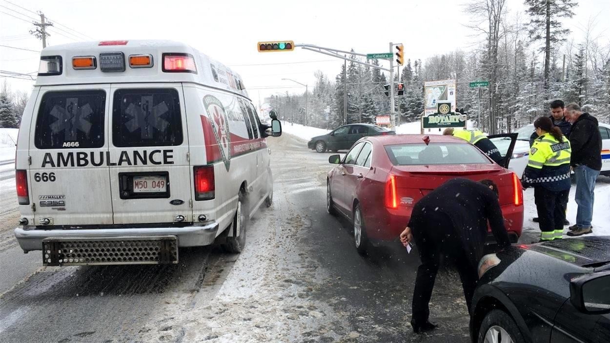 Une ambulance, en hiver, est arrêtée près d'une voiture. Les paramédicaux parlent au conducteur.