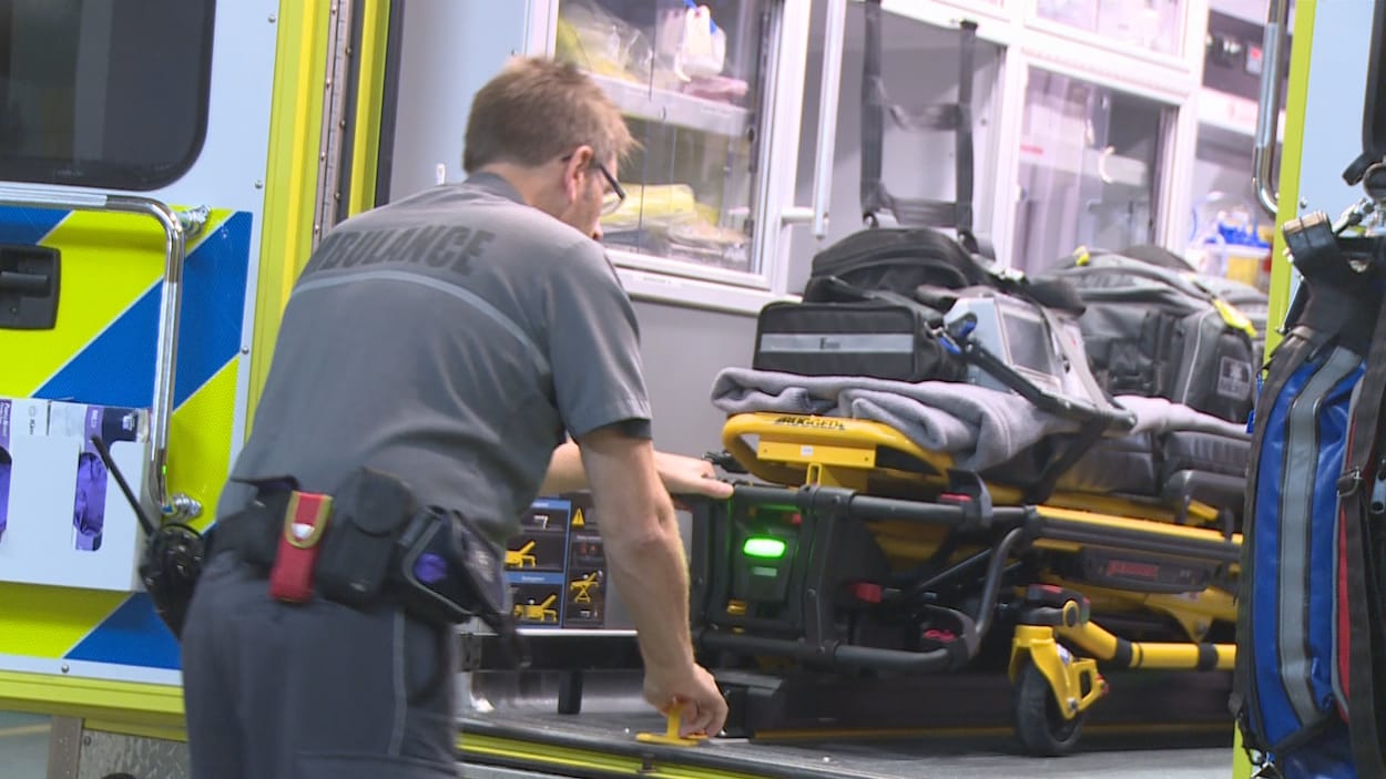 Un ambulancier tire une civière dans une ambulance.