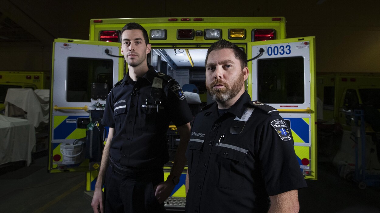 Marc-André Gaudreau et Mathieu Goyer posant à l'arrière d'une ambulance dans un garage.