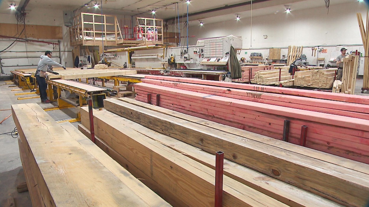 Un travailleur s'affaire au-dessus de planches de bois dans l'usine de l'entreprise AmeriCan Structures.