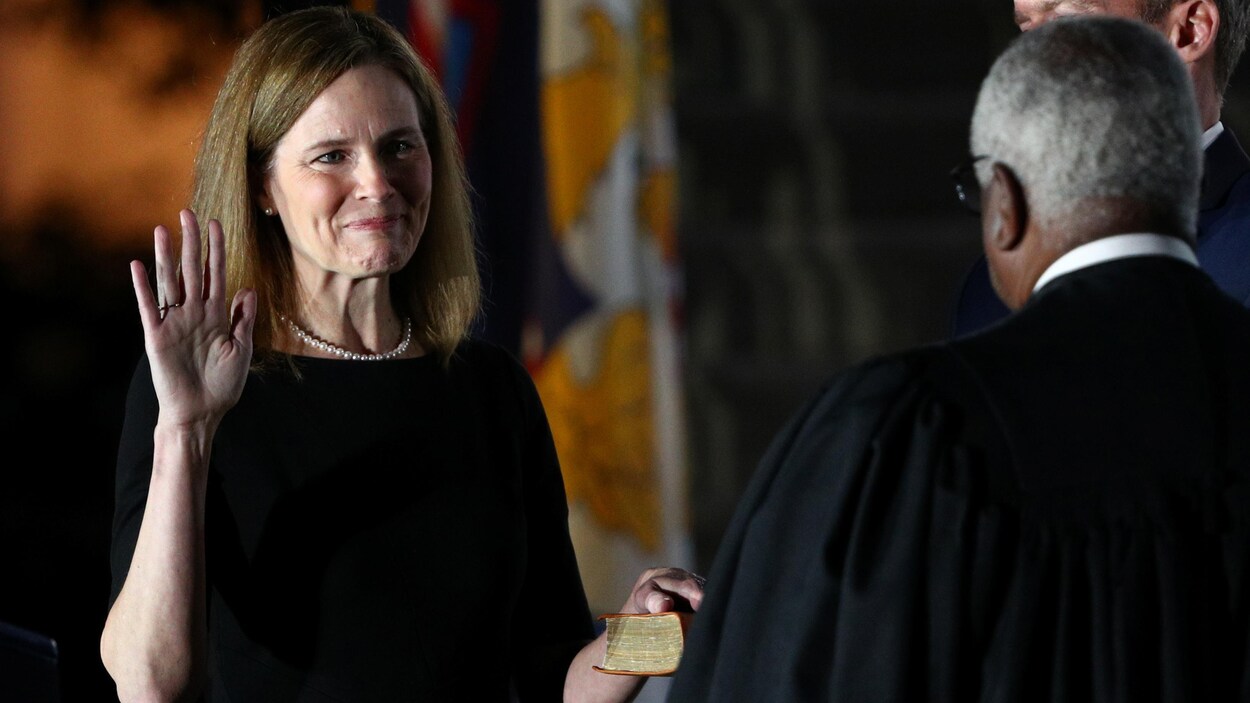 Amy Coney Barrett lève la main droite et pose la main gauche sur la Bible.