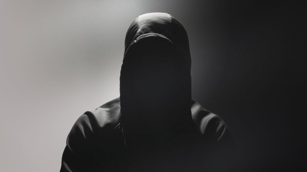 Un homme avec le visage caché portant un capuchon. Un homme avec le visage caché portant un capuchon.