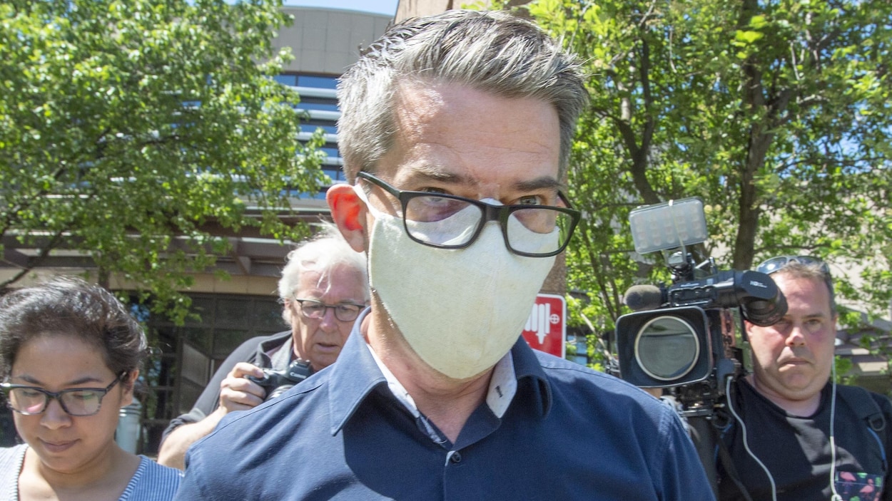 Portant un masque, M. Boisclair regarde au loin.