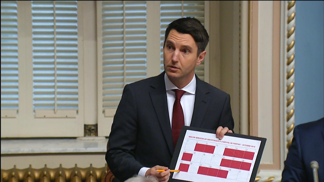 Un homme tient un calendrier dont une douzaine de cases sont rouges.