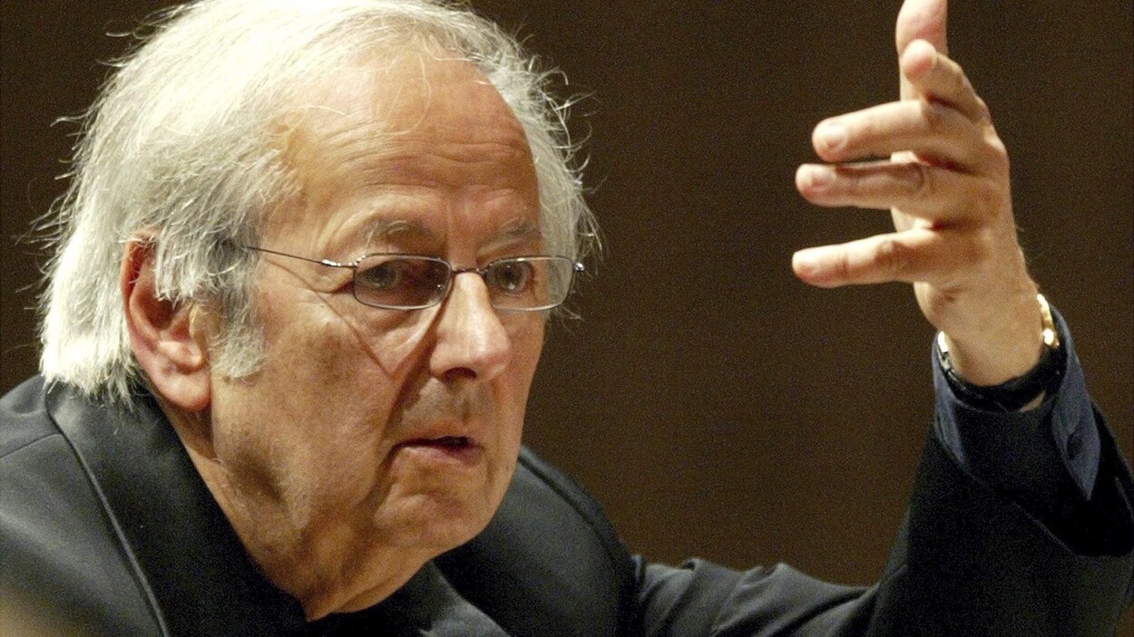 Le chef d'orchestre dirige des musiciens, la main levée.