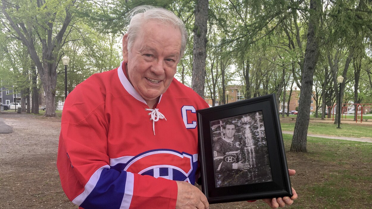André Pronovost tient dans ses mains une photo en noir et blanc de Maurice Richard et la Coupe Stanley.