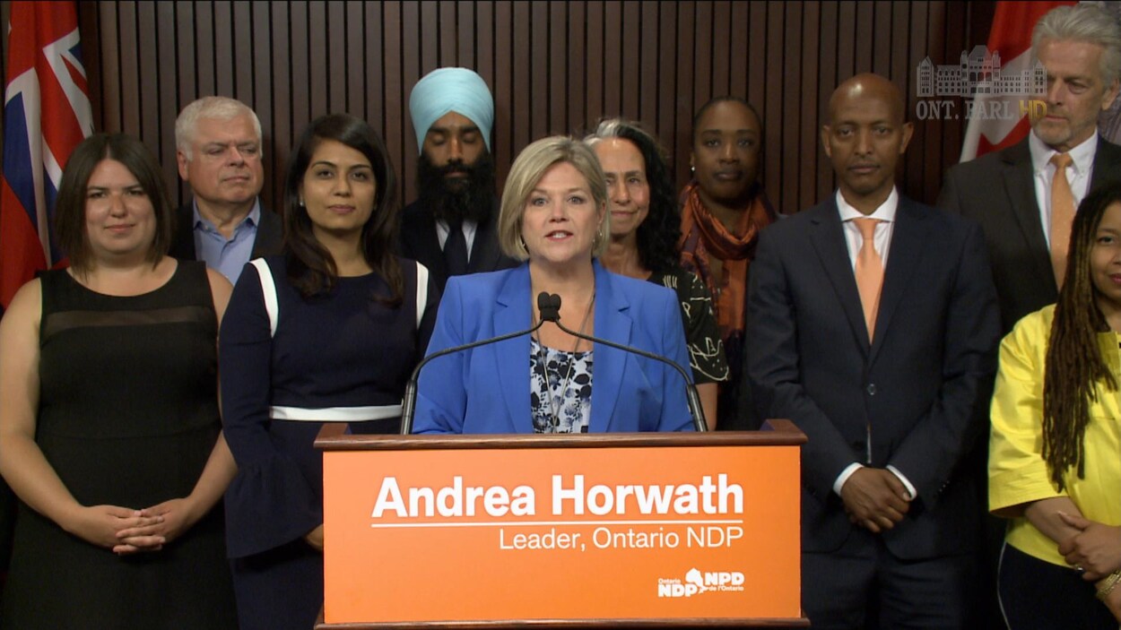 Andrea Horwath derrière un podium et devant un groupe de personnes.