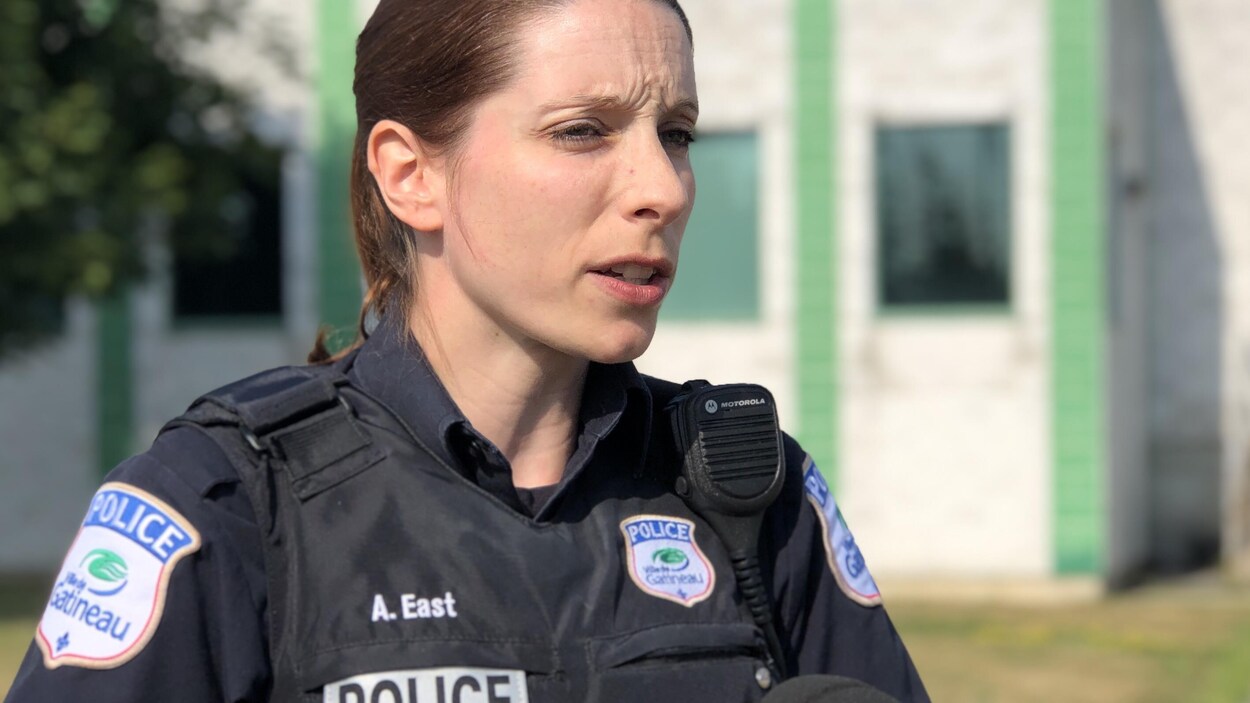 Andrée East répond aux question d'une journaliste devant le poste de police.