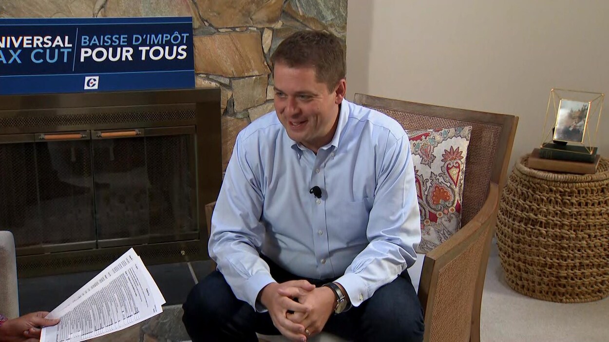 Andrew Scheer est assis dans un fauteuil dans un salon qui comporte un foyer.