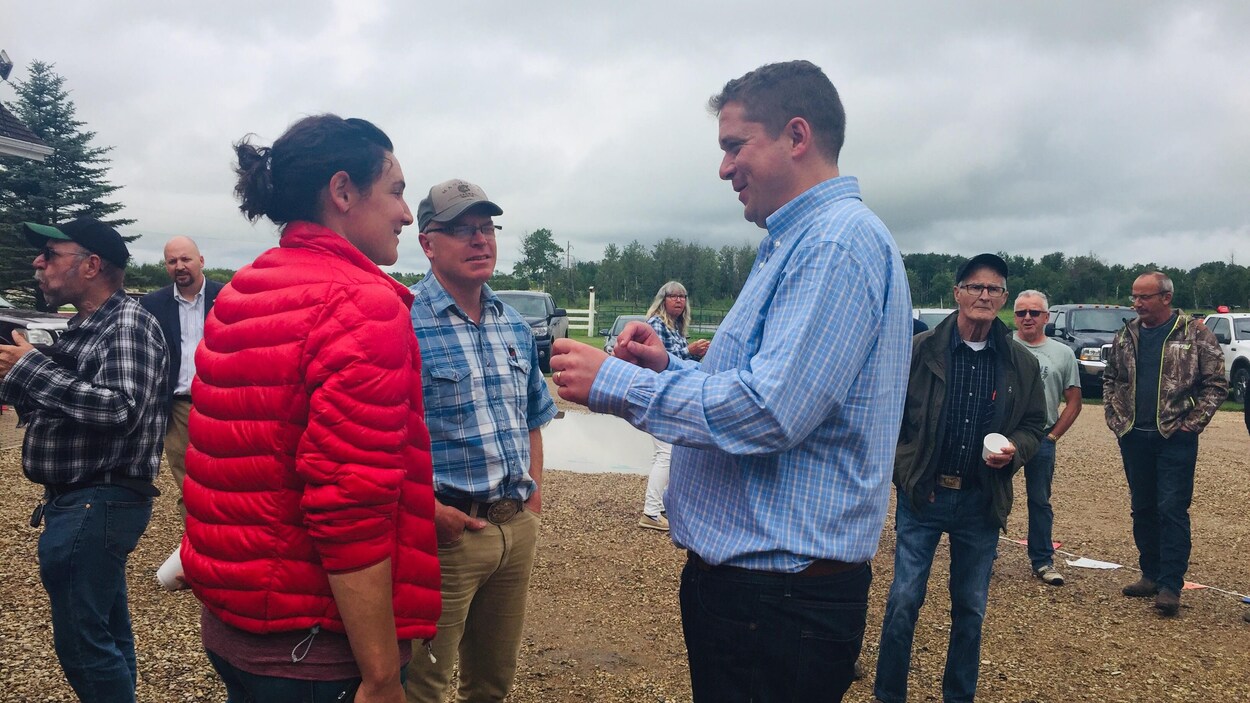 Andrew Scheer, debout, parle à quelques Saskatchewanais en plein air.